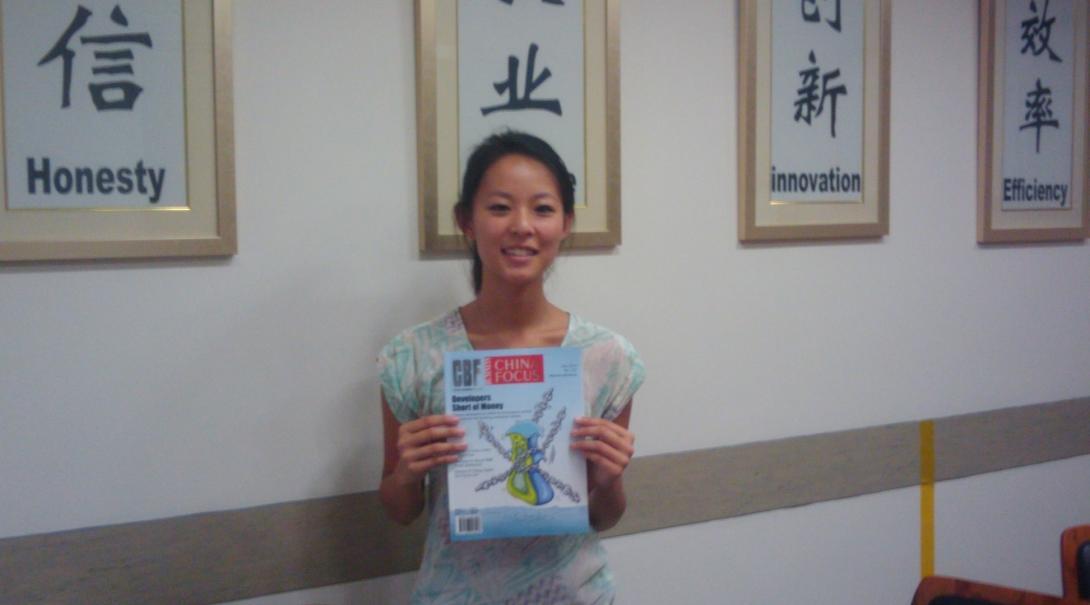 A Projects Abroad journalism intern in China poses with a magazine An intern in China takes a picture with a magazine at her placement